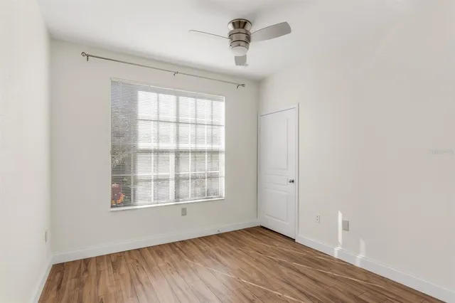 an empty room with wooden floor cabinet and windows