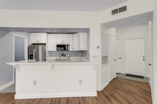 a view of kitchen with stainless steel appliances granite countertop cabinets and wooden floor