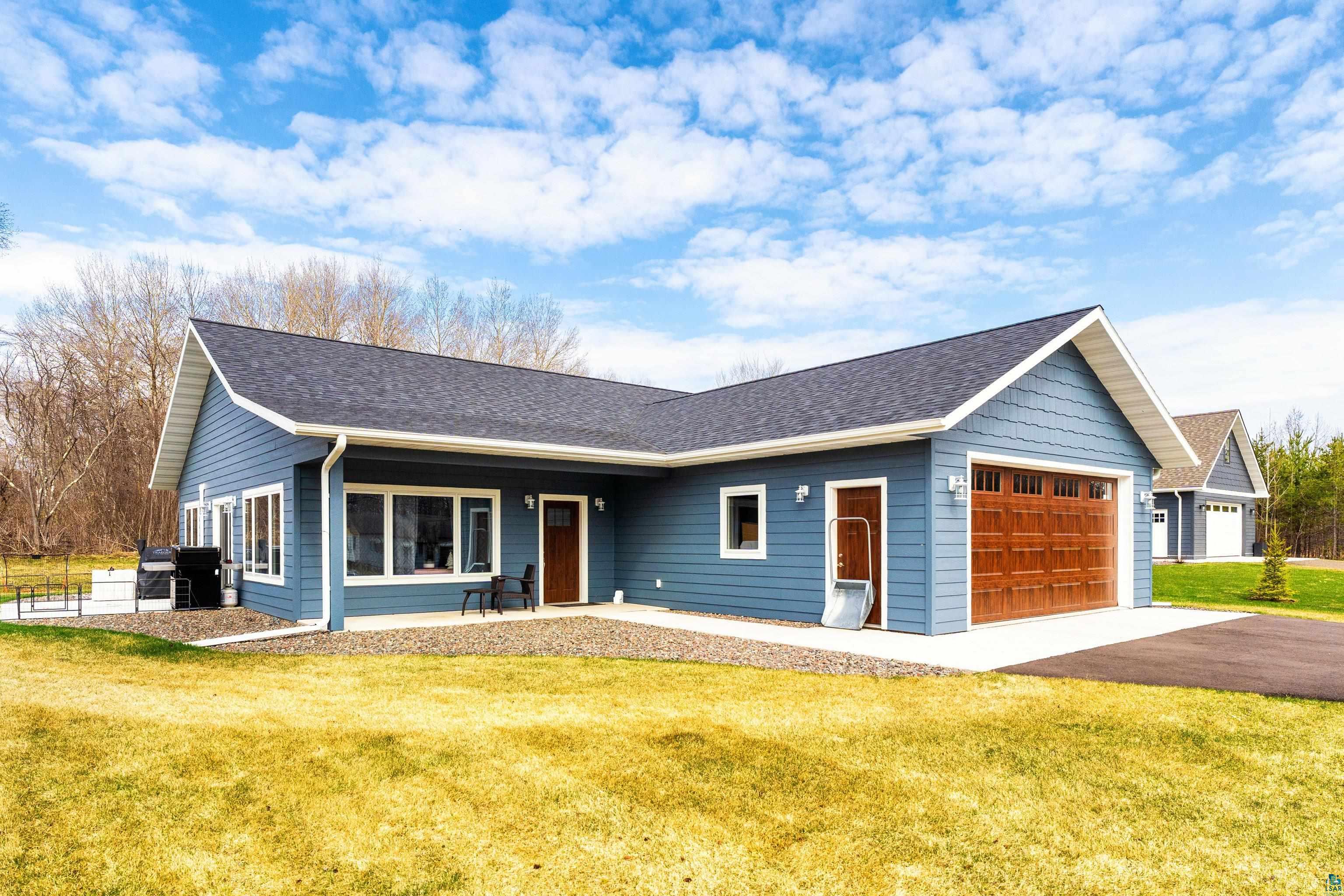 3829 Stebner Road Hermantown, MN 55811 - Photo 26 of 28 Contemporary home featuring blue horizontal siding, white trim, a dark shingle roof, and an attached two-car garage with a wood-finish door