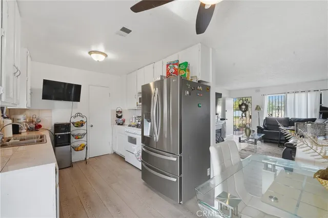 a kitchen with stainless steel appliances a refrigerator a stove a sink a dining table and chairs with wooden floor