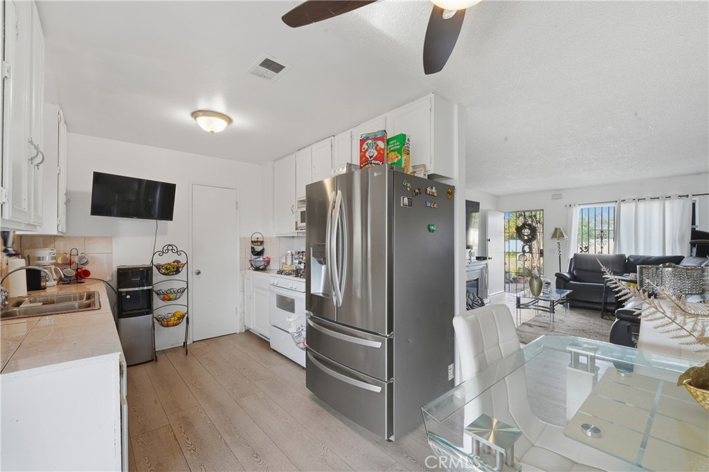 645 West Winchester Drive Rialto, CA 92376 - Photo 8 of 22 a kitchen with stainless steel appliances a refrigerator a stove a sink a dining table and chairs with wooden floor