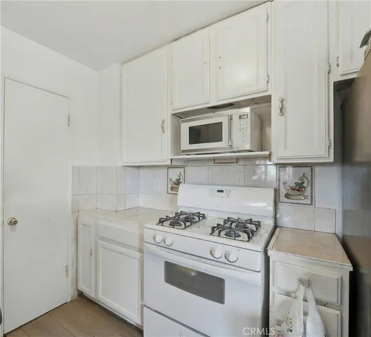 a kitchen with stainless steel appliances white cabinets and a stove a oven with white countertops