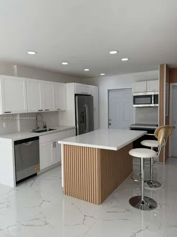 a kitchen with kitchen island granite countertop wooden cabinets and white stainless steel appliances