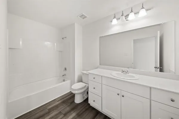 a bathroom with a double vanity sink a toilet and a bathtub