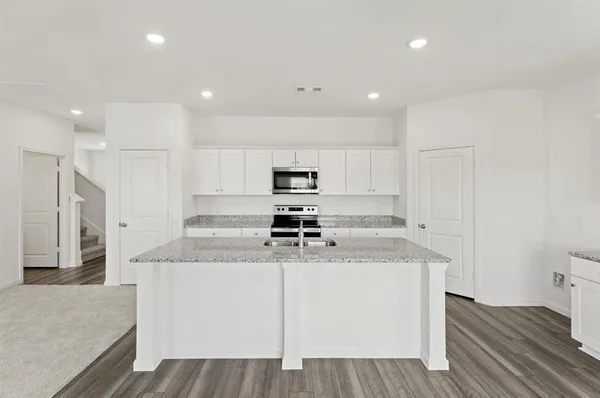 a kitchen with stainless steel appliances a sink stove refrigerator and white cabinets with wooden floor