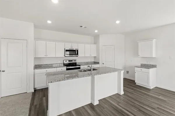 a kitchen with granite countertop stainless steel appliances sink stove microwave and cabinets