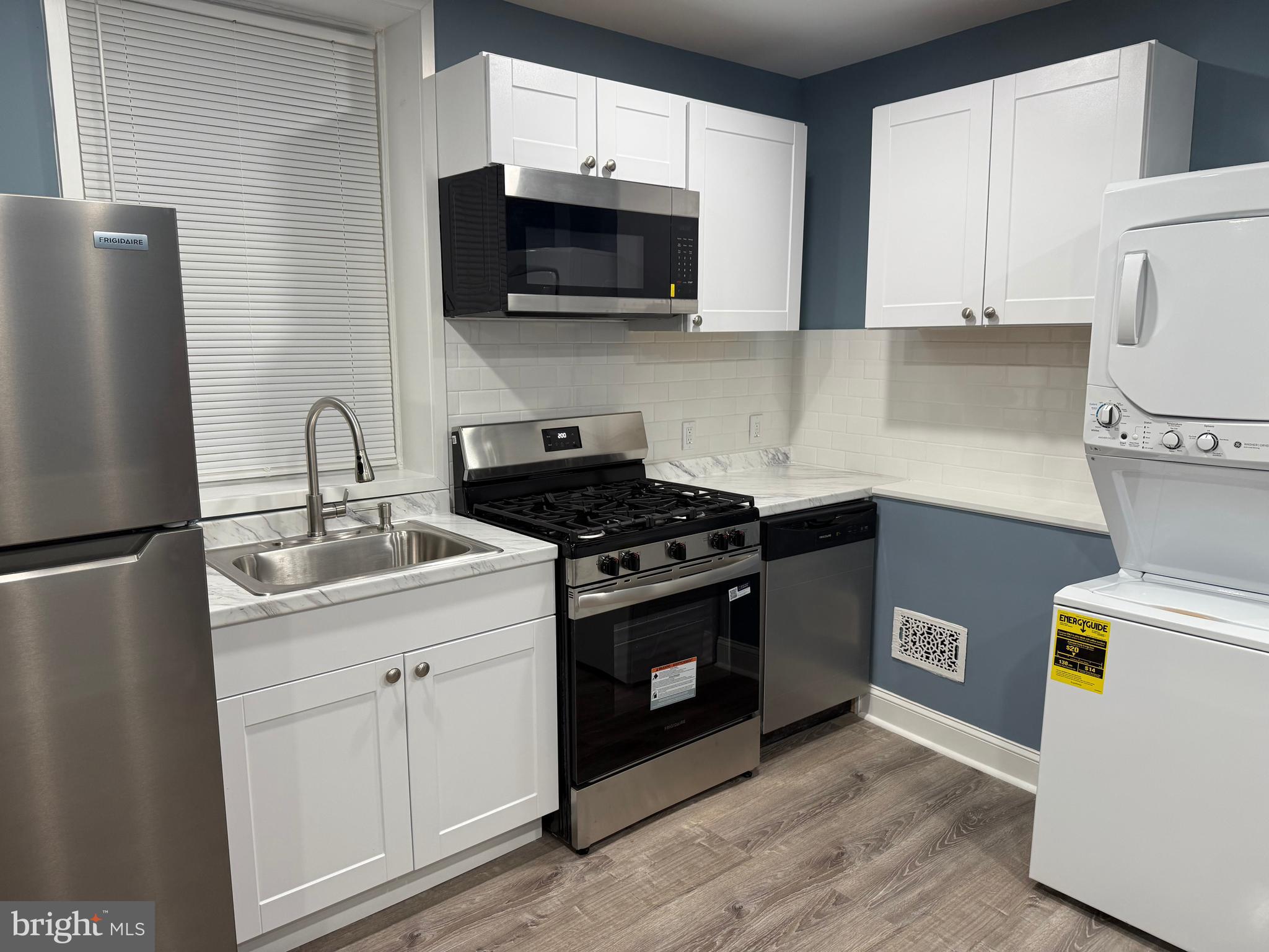 5332 Pine Street, Unit 2 Philadelphia, PA 19143 - Photo 7 of 21 a kitchen with stainless steel appliances a sink a stove a microwave and wooden cabinets
