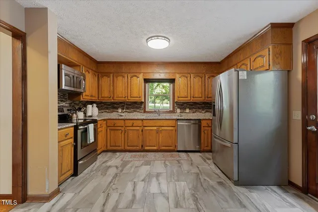 a kitchen with stainless steel appliances granite countertop a refrigerator and a stove top oven