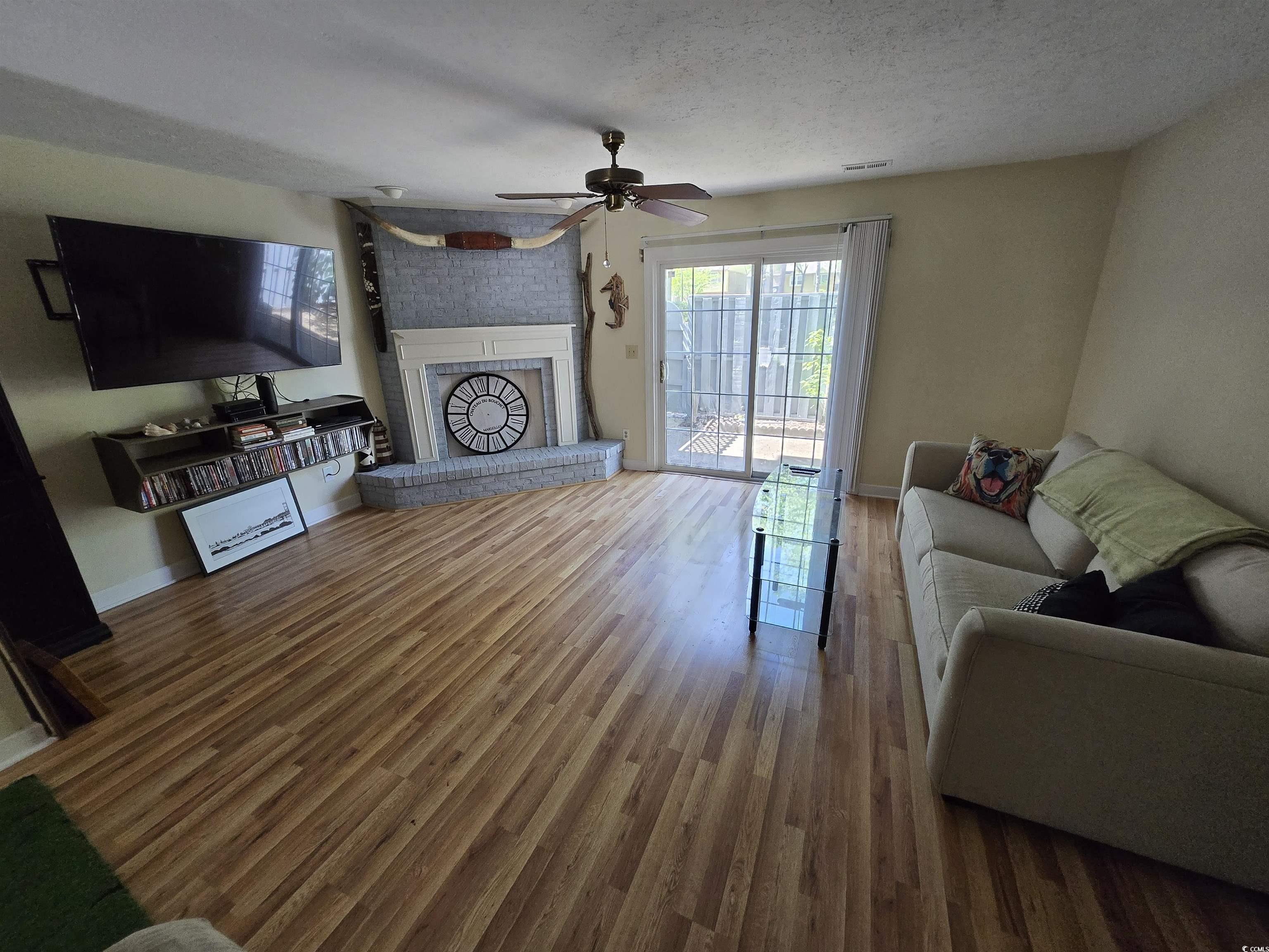 830 44th Avenue North Myrtle Beach, SC 29577 - Photo 2 of 13 Living room with wood finished floors, a textured ceiling, a fireplace, and ceiling fan