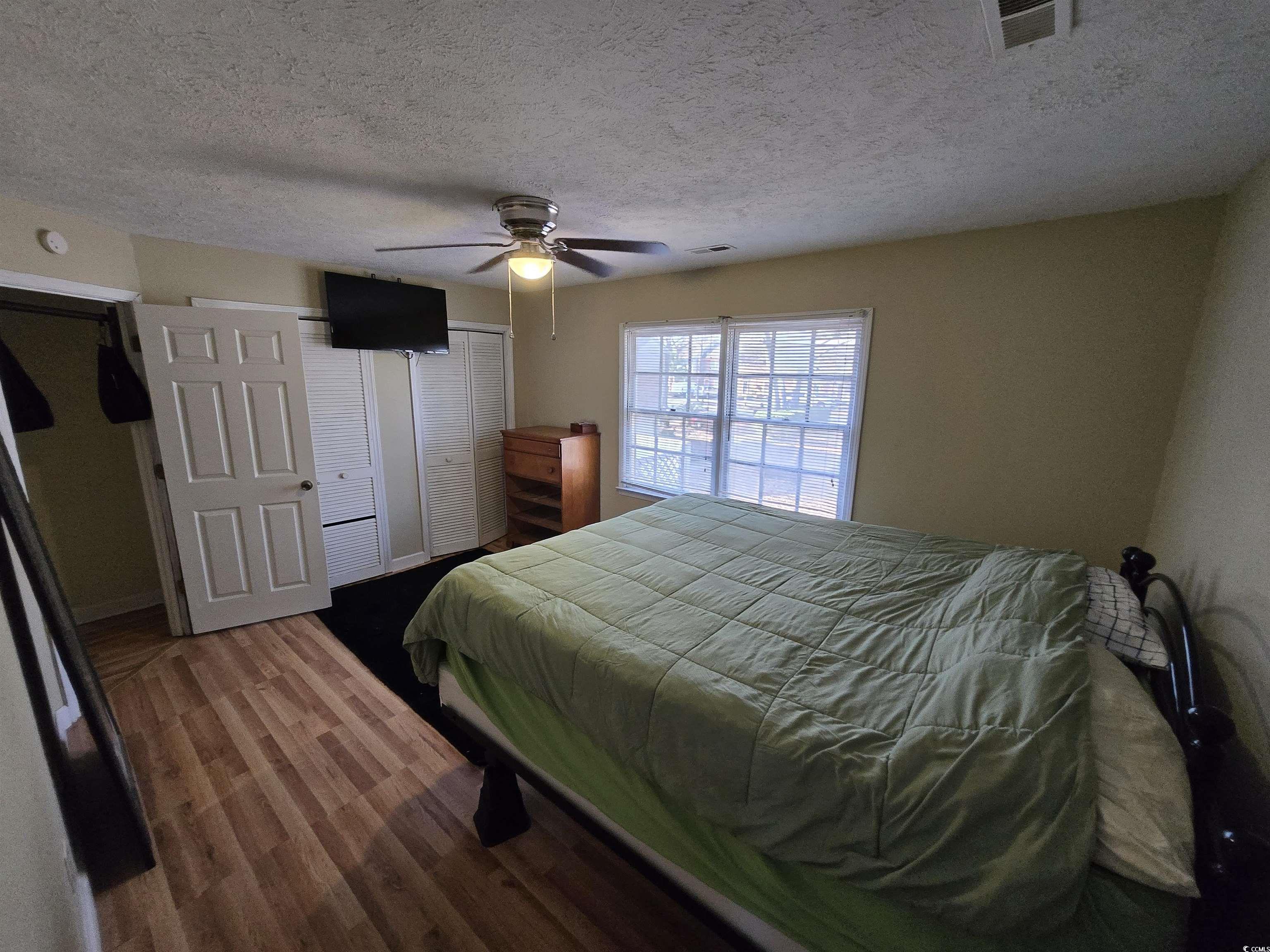 830 44th Avenue North Myrtle Beach, SC 29577 - Photo 6 of 13 Bedroom with a textured ceiling, multiple closets, dark wood finished floors, and a ceiling fan
