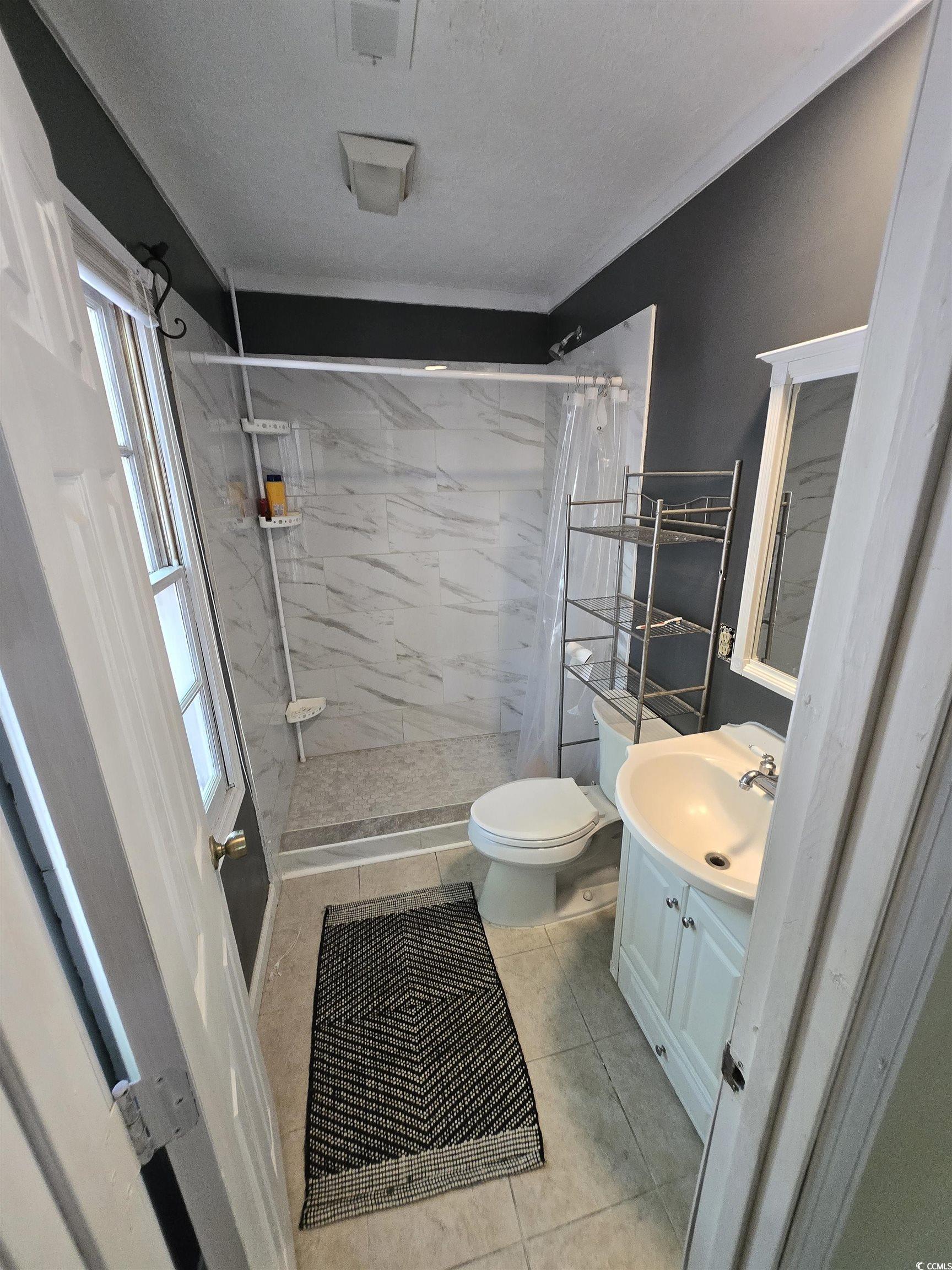 830 44th Avenue North Myrtle Beach, SC 29577 - Photo 7 of 13 Full bath with a shower stall, vanity, and light tile patterned floors