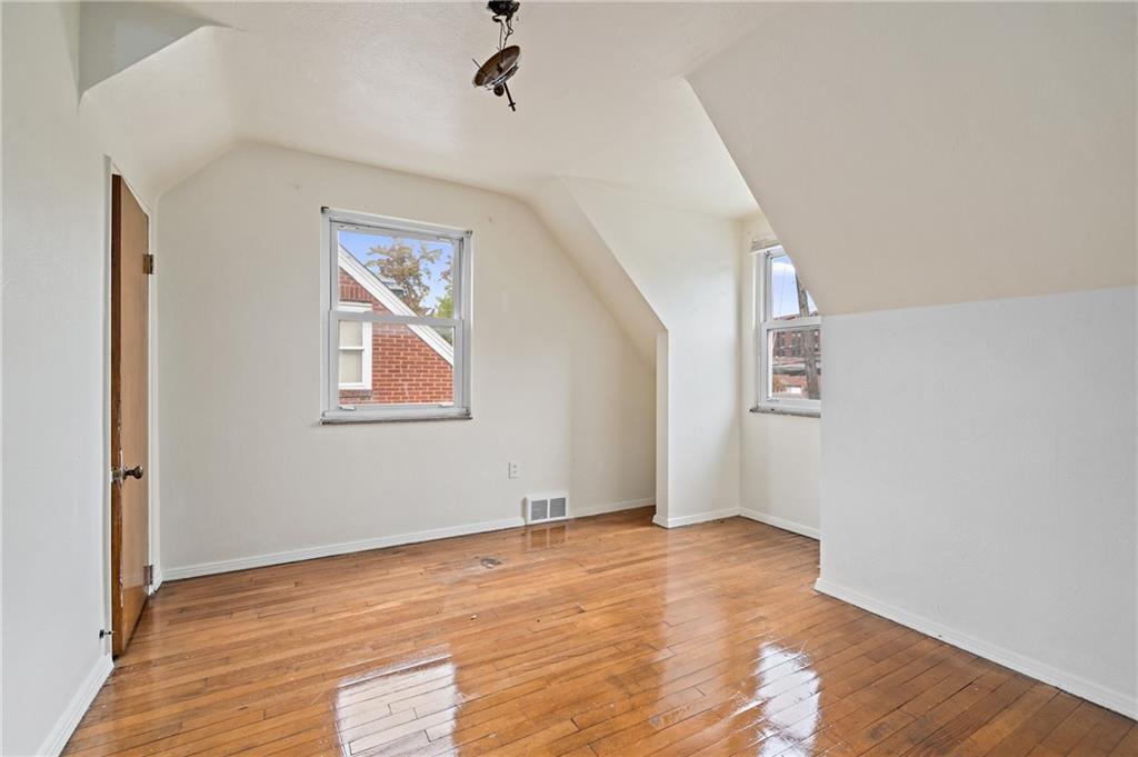 105 Delafield Road Pittsburgh, PA 15215 - Photo 14 of 18 an empty room with wooden floor chandelier fan and windows