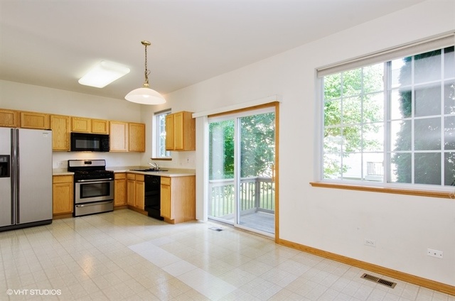 296 Evergreen Circle Gilberts, IL 60136 - Photo 3 of 10 a open kitchen with stainless steel appliances granite countertop a stove top oven a sink dishwasher a dining table and chairs with wooden floor