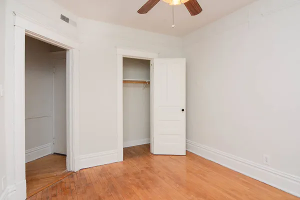 an empty room with closet and a chandelier fan