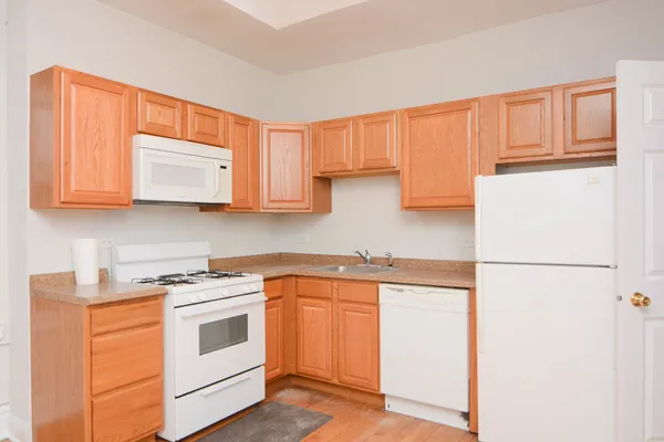 a kitchen with stainless steel appliances granite countertop white cabinets sink and a refrigerator