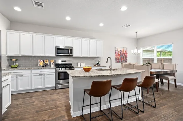 a kitchen with stainless steel appliances granite countertop a stove a sink a microwave a dining table and chairs