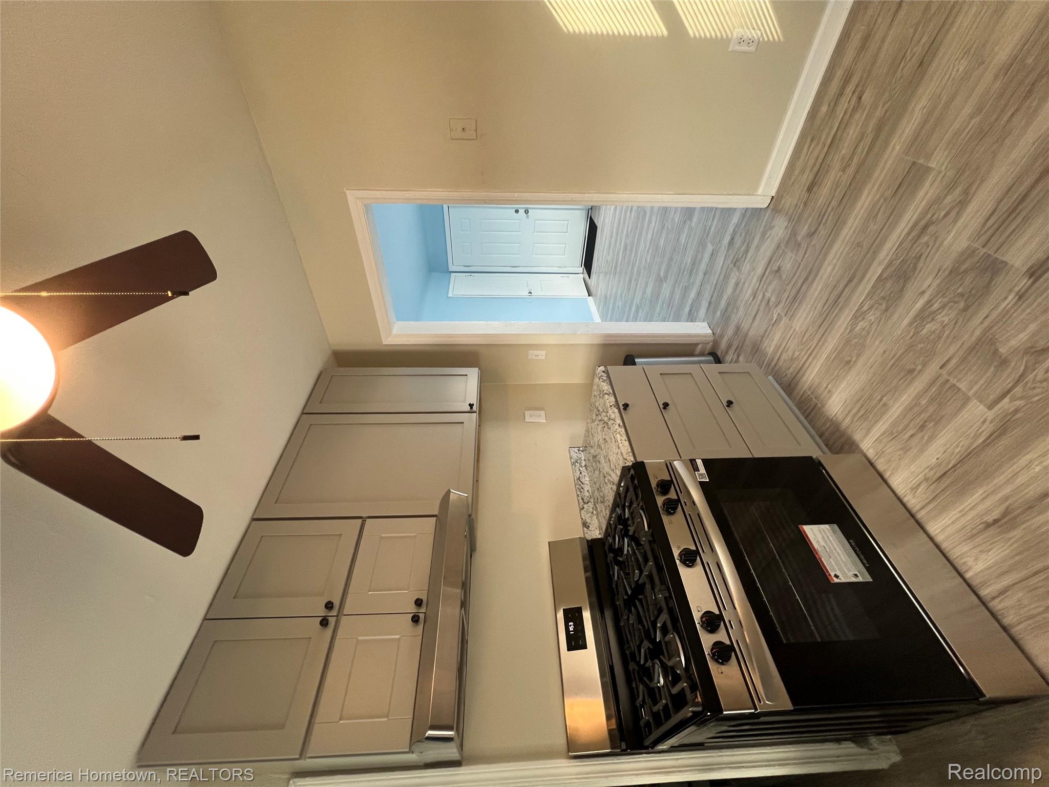 26159 Stanford Street Inkster, MI 48141 - Photo 5 of 16 Kitchen with gray cabinets, stainless steel gas range, ceiling fan, light wood-type flooring, and light stone countertops