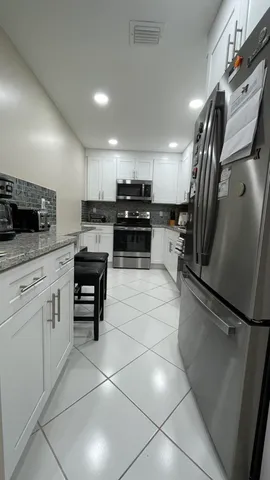 a kitchen with granite countertop a refrigerator and a stove top oven