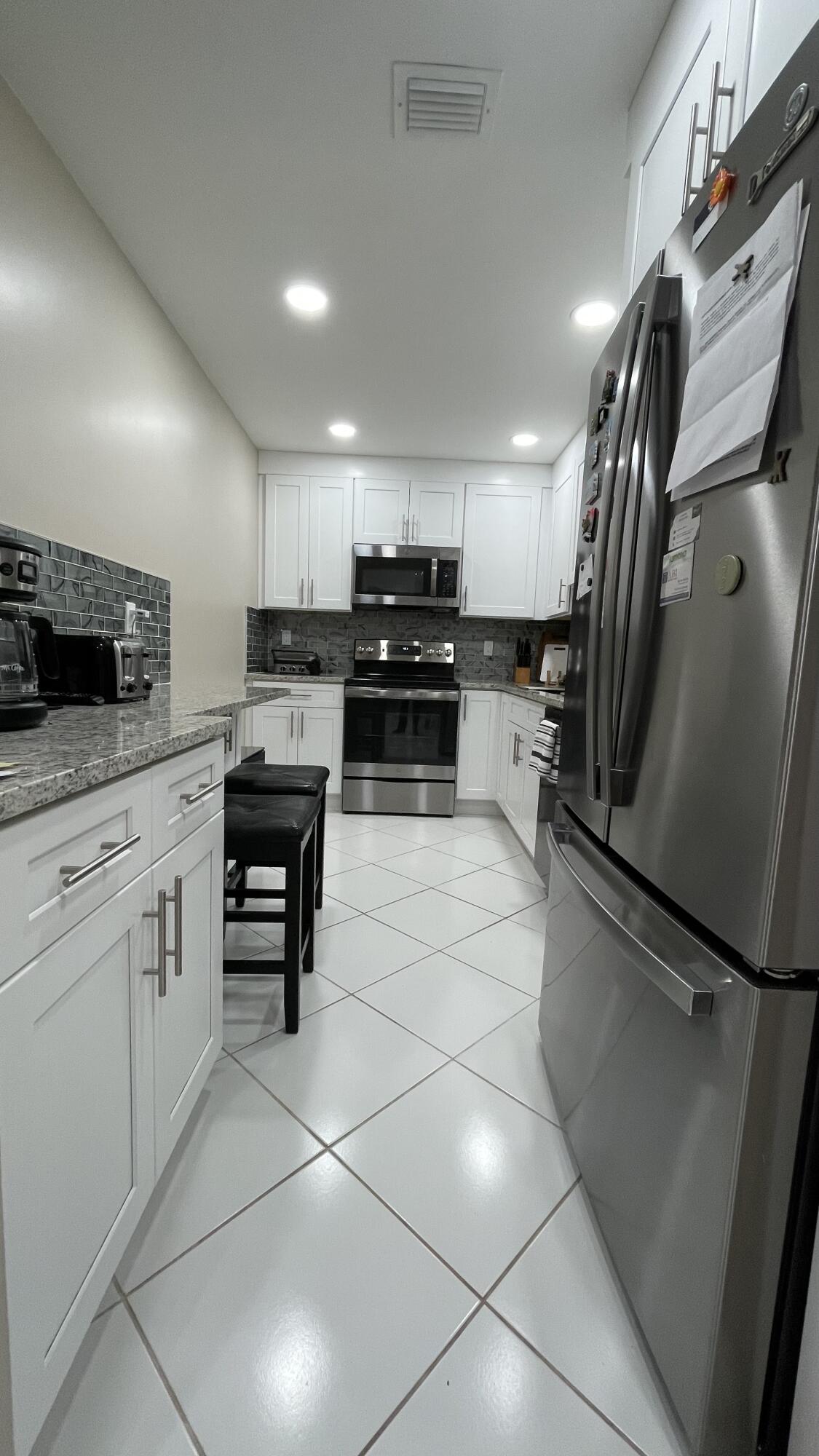 10140 South 44th Drive, Unit 372 Boynton Beach, FL 33436 - Photo 8 of 19 a kitchen with granite countertop a refrigerator and a stove top oven