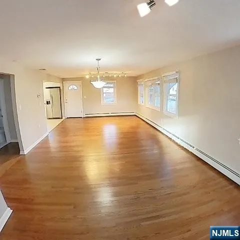 a view of an empty room with window and wooden floor