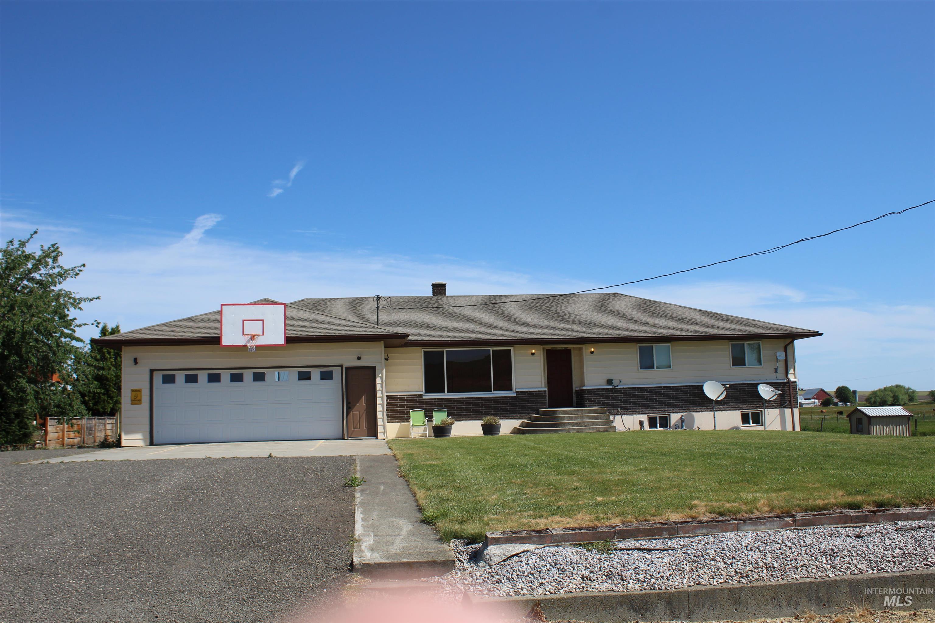 Single story home featuring a garage, a front yard, driveway, and brick siding
