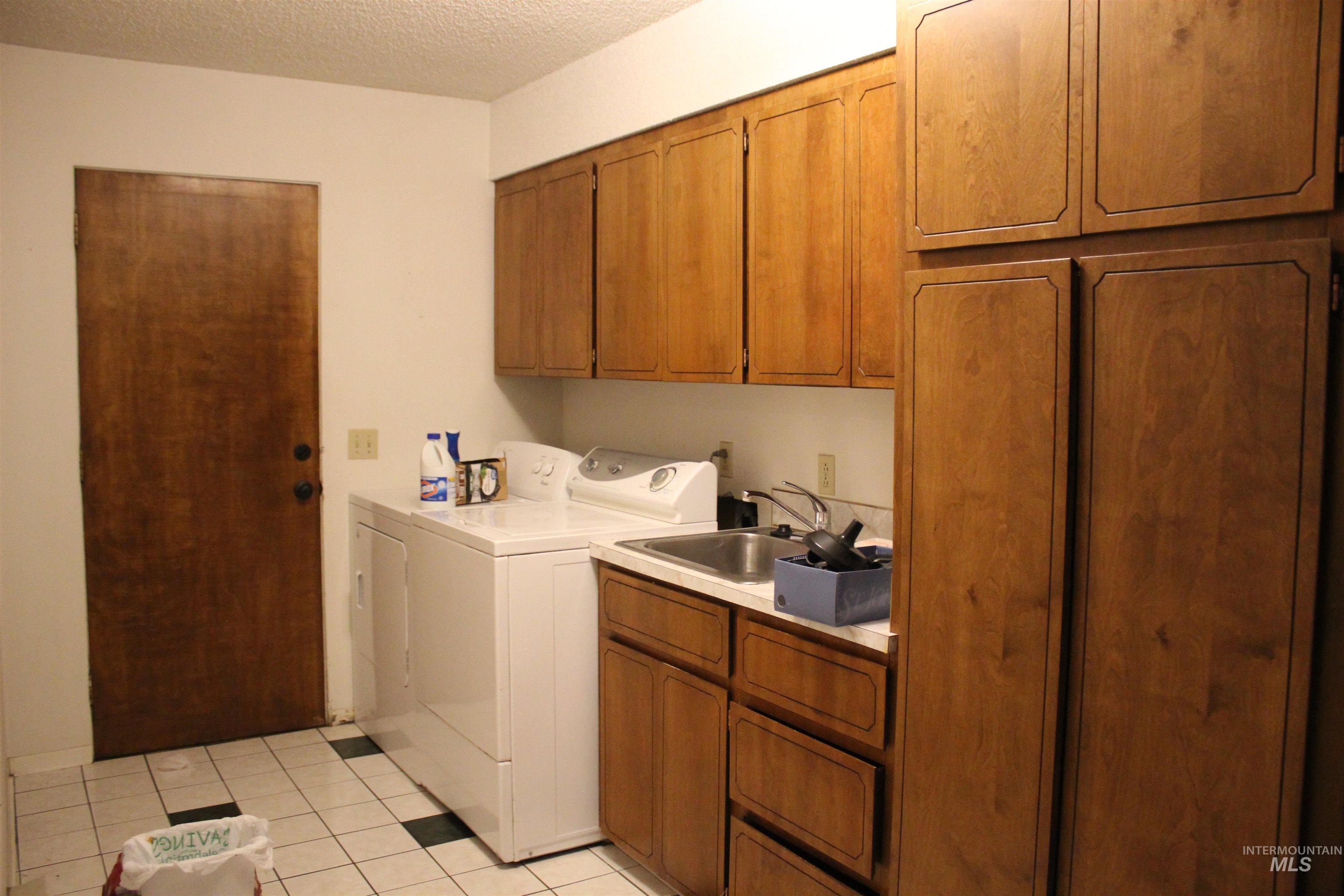 1034 Greencreek Road Greencreek, ID 83533 - Photo 6 of 42 Laundry area featuring cabinet space, washer and clothes dryer, light tile patterned floors, and a textured ceiling
