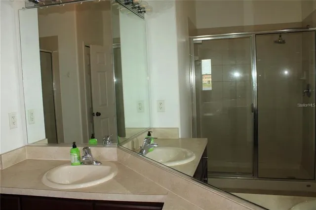 a bathroom with a granite countertop sink a mirror and a shower