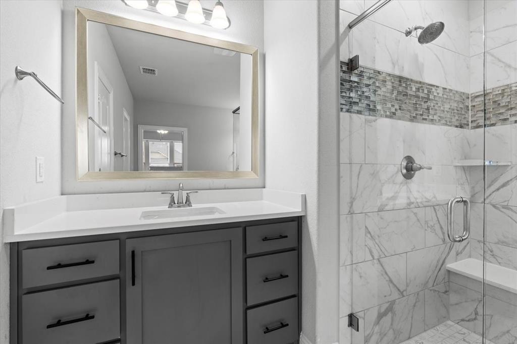 620 Shadow Trail Frisco, TX 75033 - Photo 19 of 36 Modern bathroom featuring a glass-enclosed shower with marble-look tile, a built-in shower bench, and a mosaic tile accent band