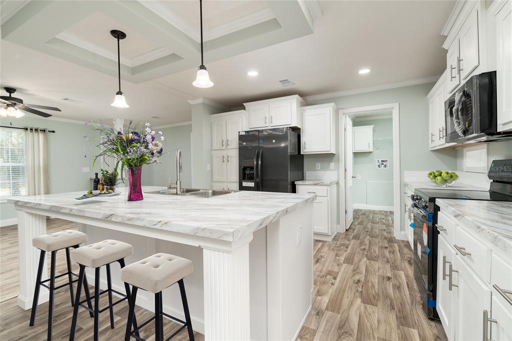 689 Eagle Watch Road Oak Hill, FL 32759 - Photo 11 of 32 a kitchen with stainless steel appliances kitchen island granite countertop a sink and a refrigerator