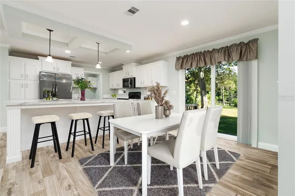 a kitchen with stainless steel appliances granite countertop a table chairs and a wooden floor