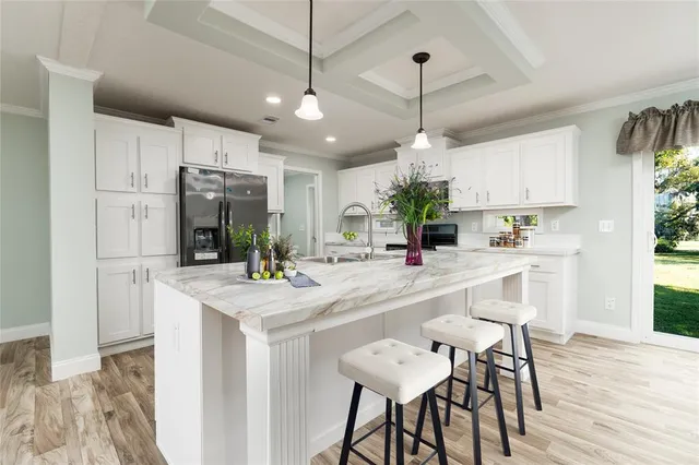 a kitchen with kitchen island a dining table chairs a sink and a window