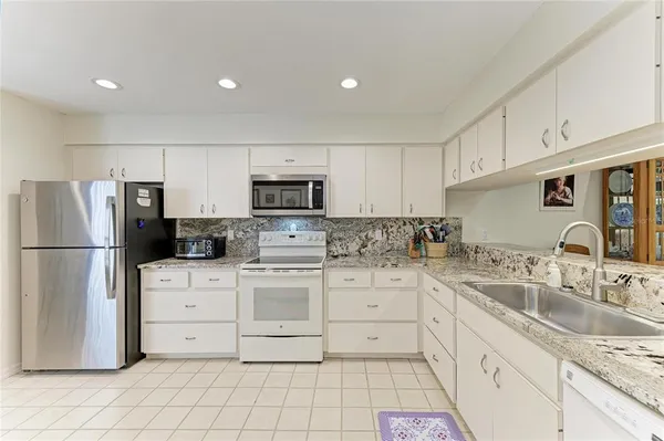 a large white kitchen with sink and refrigerator