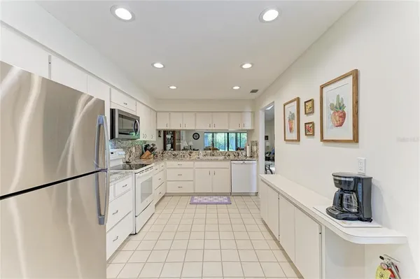 a kitchen with white cabinets and refrigerator