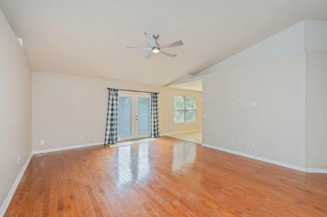 a view of an empty room with wooden floor and a window