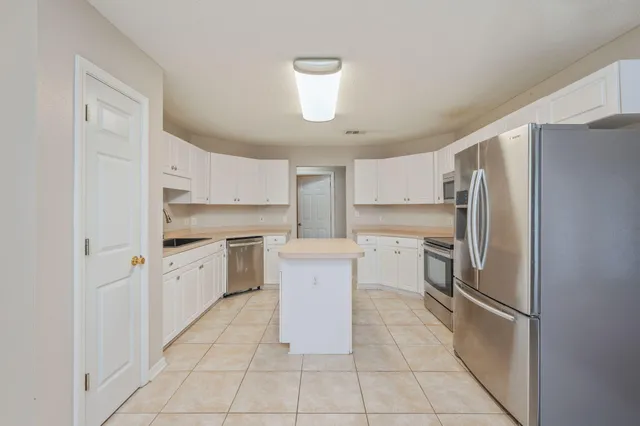 a kitchen with white cabinets and refrigerator