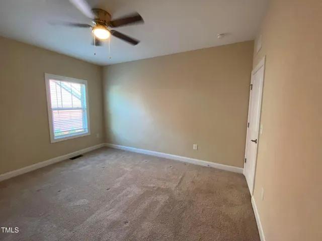 an empty room with a window and a fan