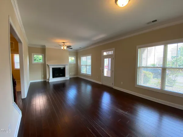 an empty room with wooden floor fireplace and windows