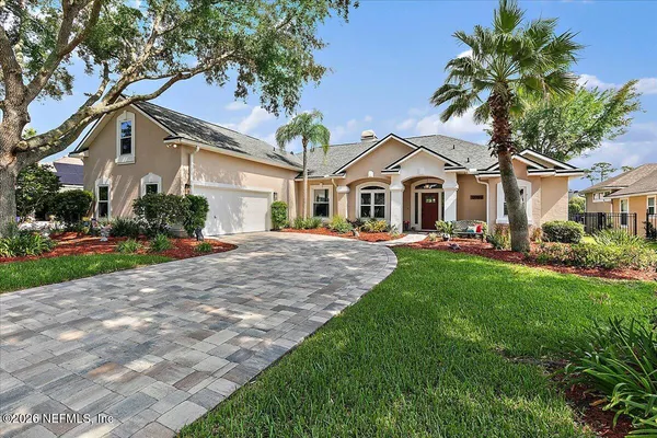a front view of a house with a yard and palm trees