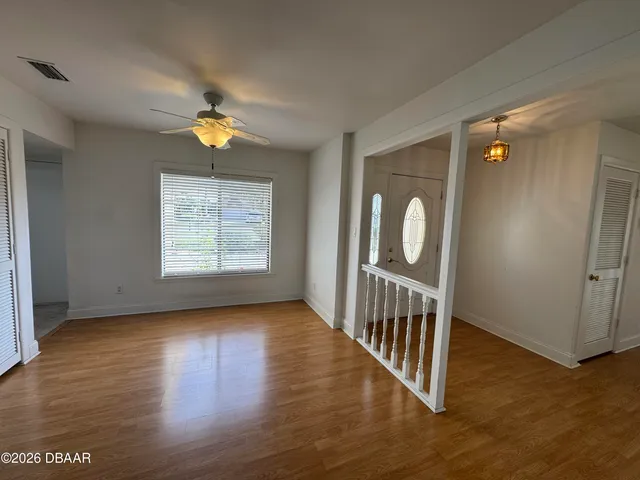 a view of an empty room with wooden floor and a window