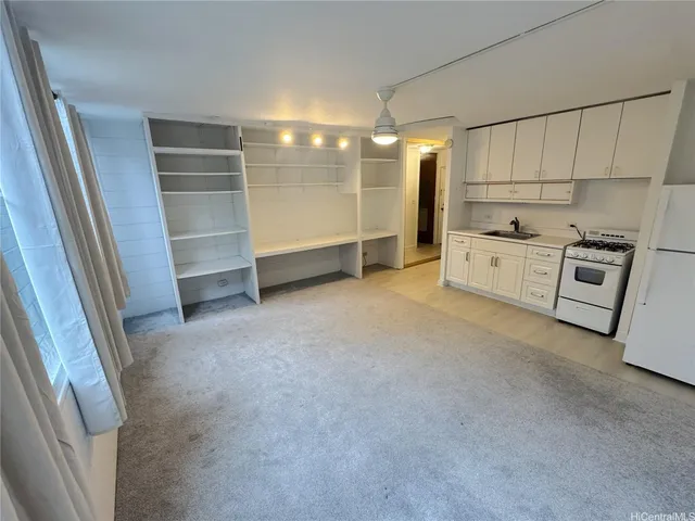 a view of a kitchen with refrigerator and white cabinets