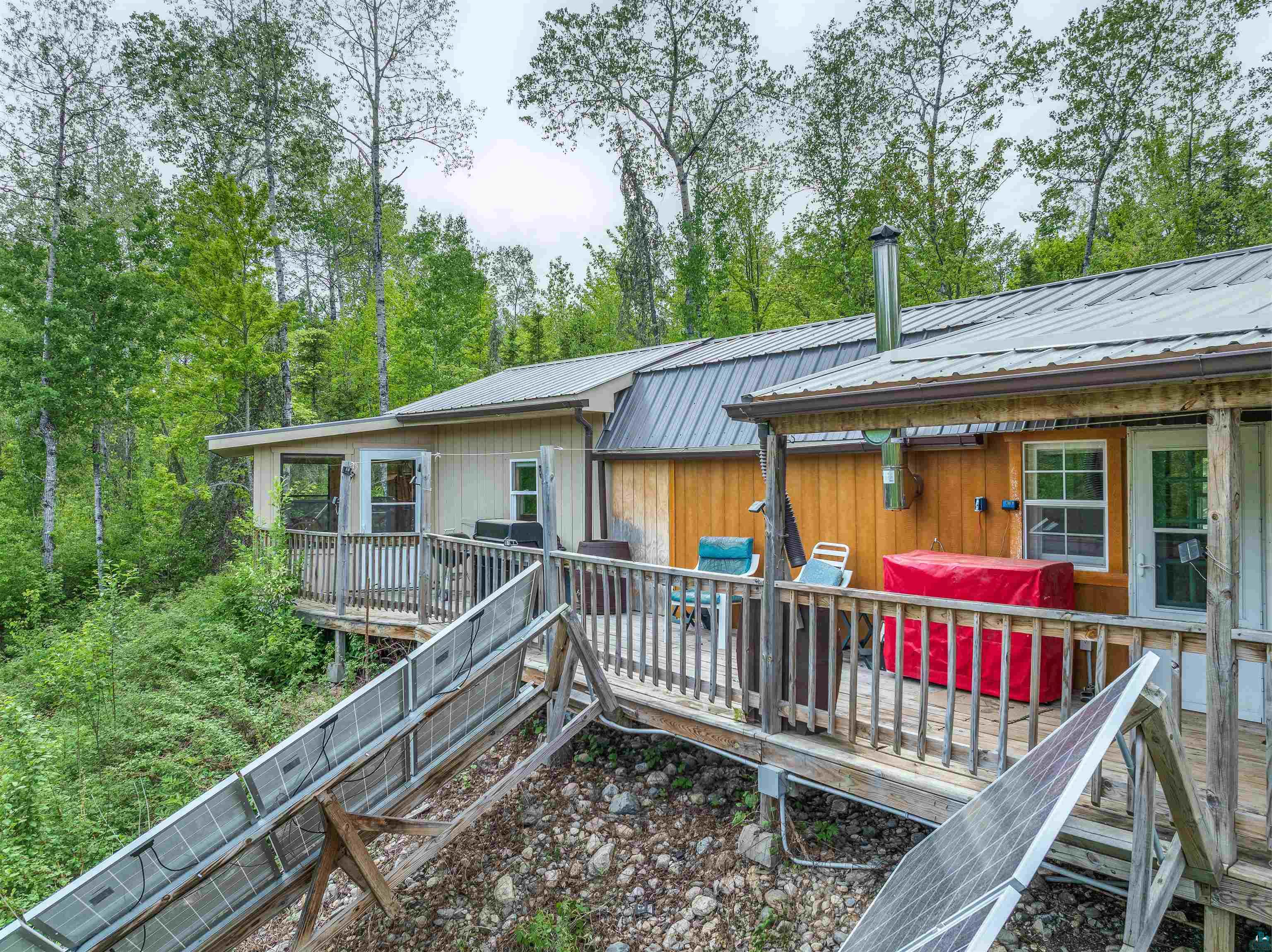 1152 Fernberg Road Ely, MN 55731 - Photo 20 of 24 Exterior deck with a metal roof and exposed wood siding, surrounded by mature trees