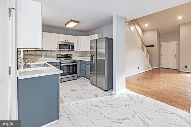 a kitchen with stainless steel appliances granite countertop a refrigerator a stove and a sink