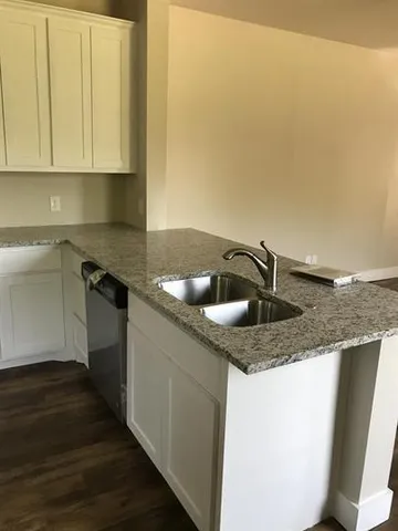 a kitchen with granite countertop a sink a stove and cabinets