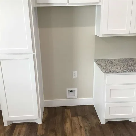a view of an empty room with wooden floor and cabinet