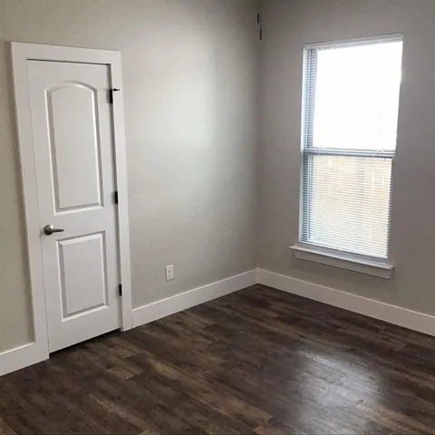an empty room with wooden floor closet and windows