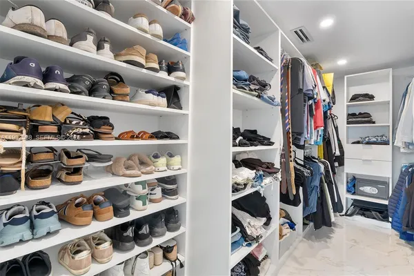a view of walk in closet with clothes and shoes
