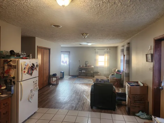 a living room with furniture a flat screen tv and a refrigerator