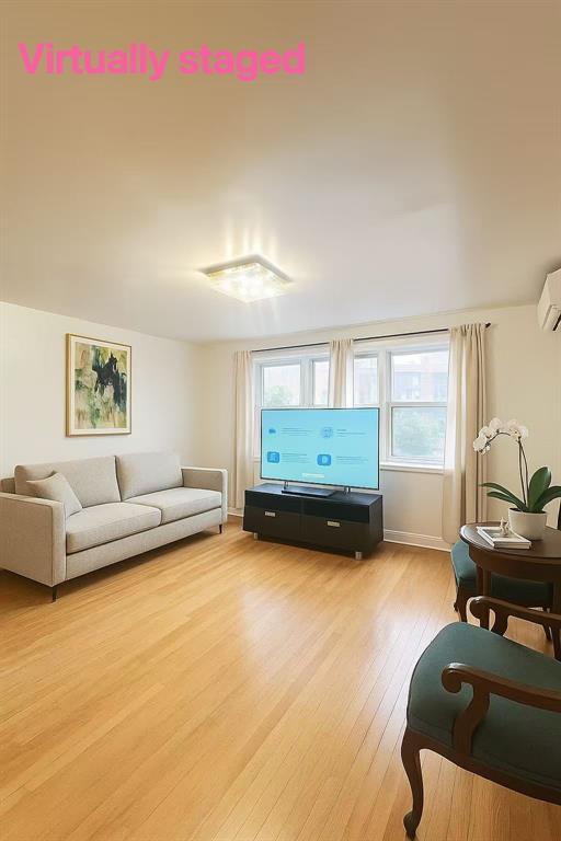 Living area with light wood-style floors and a wall mounted air conditioner