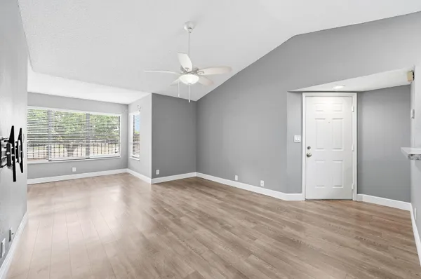 a view of an empty room with wooden floor and a window