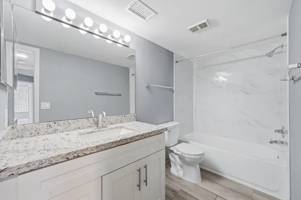 a bathroom with a granite countertop sink a toilet and shower